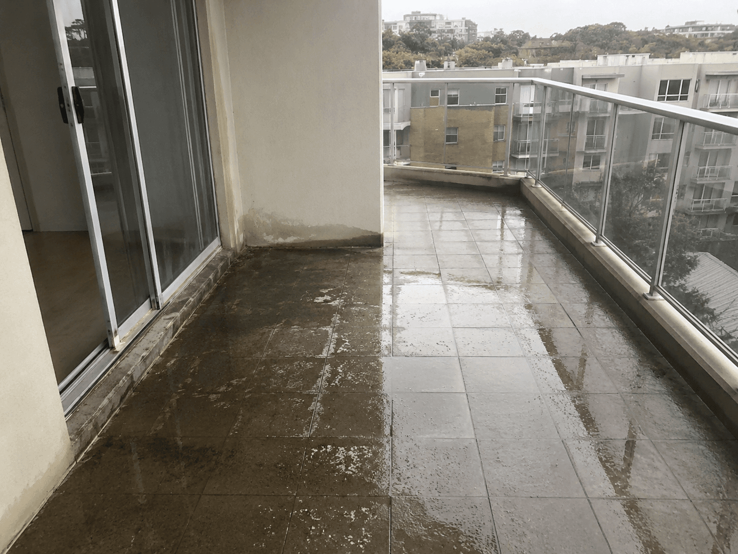Water leaking from an apartment balcony with cracked tiles and a failed waterproofing membrane